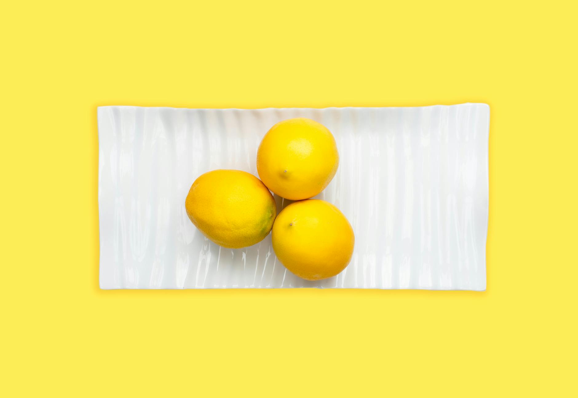 Fresh lemons arranged on a white plate, symbolizing the citrus-inspired design of relaxing adult toys
