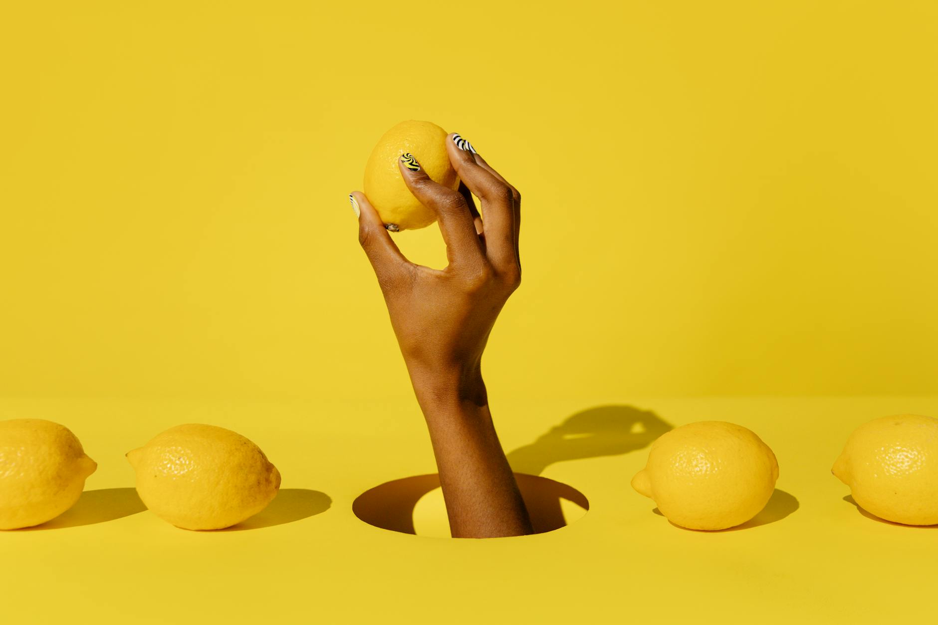 Yellow silicone lemon vibrator surrounded by fresh fruit on a bright yellow background