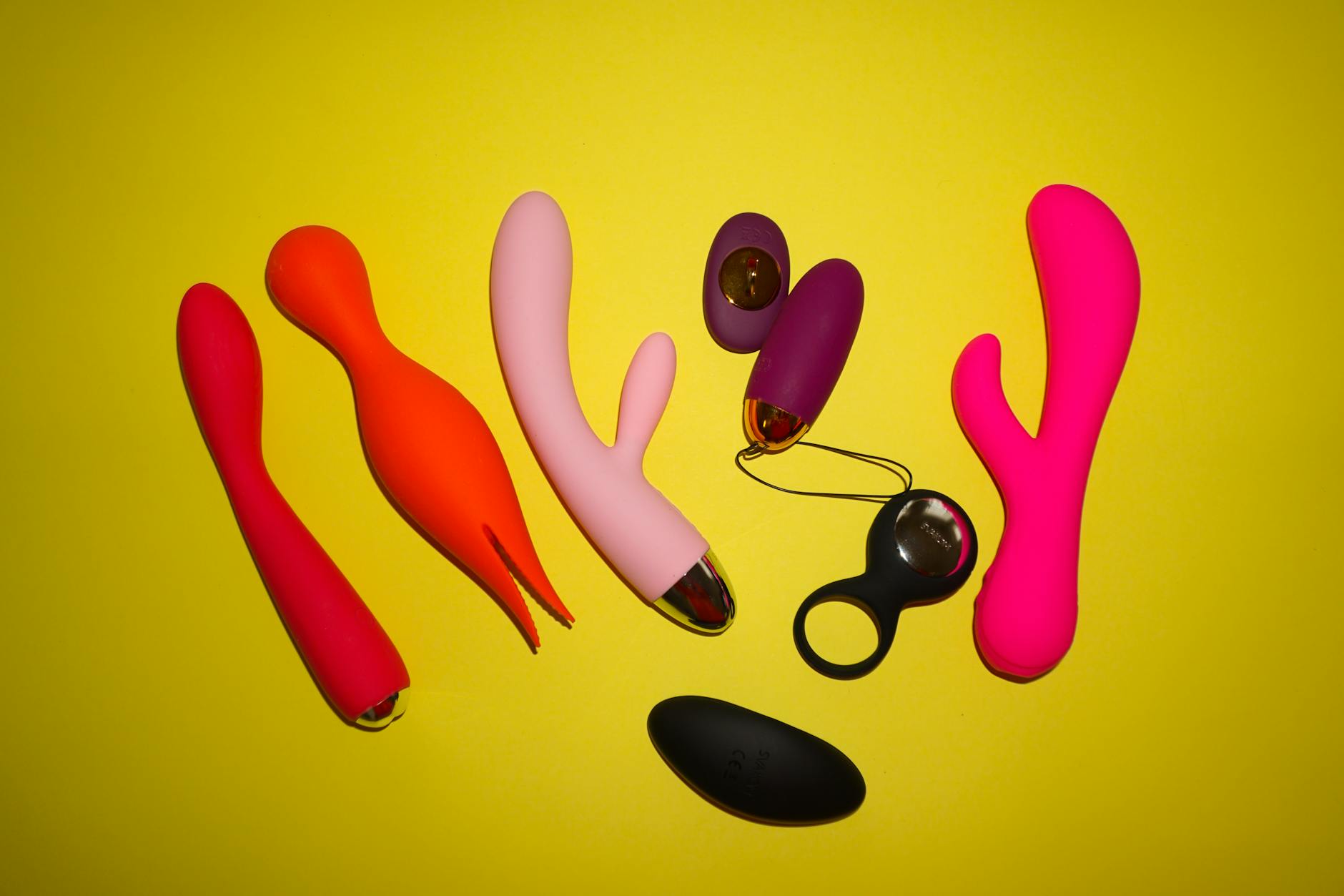 Colorful vibrators displayed on a bright yellow background, showcasing diverse pleasure tools for different bodies.